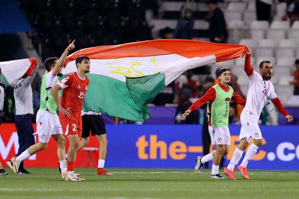 塔吉克球员（白色球衣）高举国旗，在球场上庆祝晋级。——照片：路透社