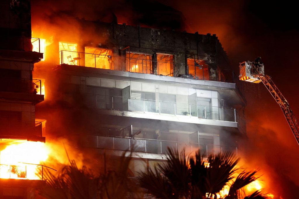 消拯人员升起云梯，全力灌救起火公寓。——照片：路透社